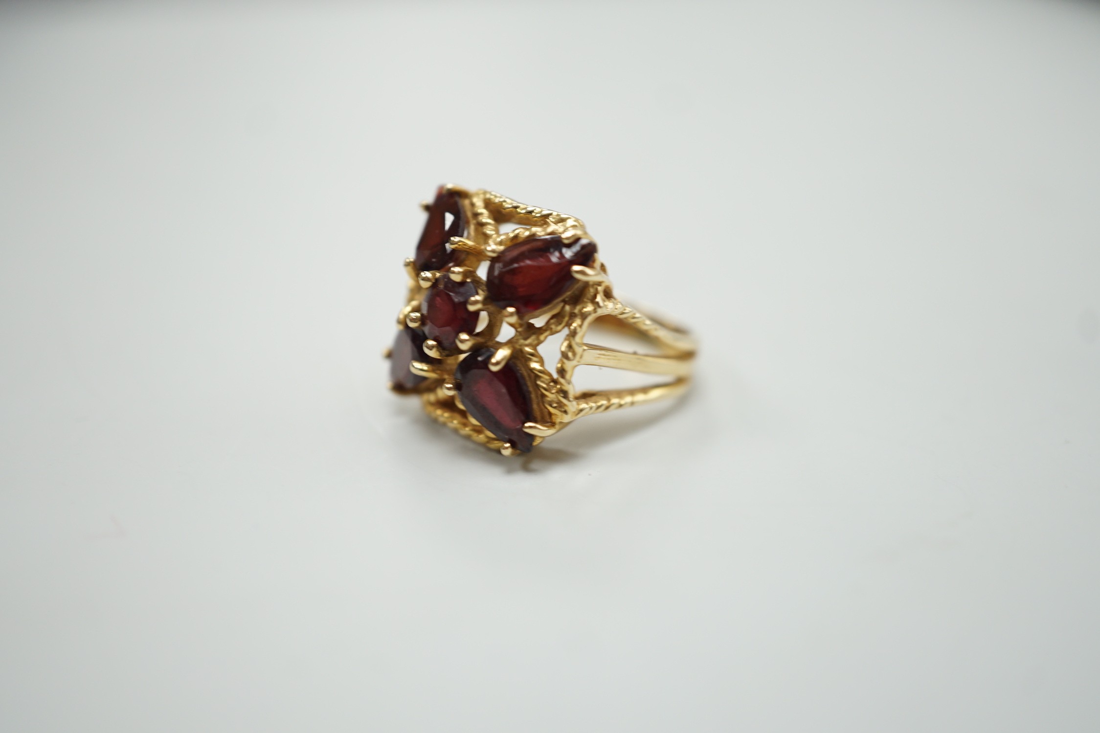 A modern 585 yellow metal and five stone garnet cluster set dress ring, size K/L